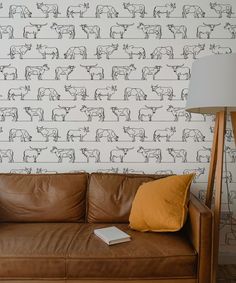 a brown leather couch sitting in front of a wall with cows drawn on the wall