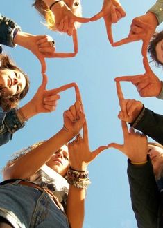 a group of people standing in a circle holding up their hands to form the shape of a star