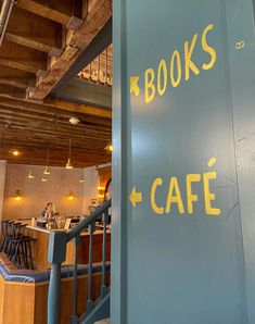 there is a sign that says books cafe next to the stairs in front of it