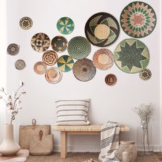 a white room with many plates on the wall and a bench in front of it