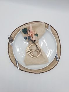 a white plate topped with a napkin and two wedding rings next to a fork and knife