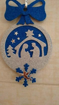 a christmas ornament with a blue ribbon hanging from it's side on a wall