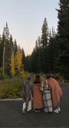 three people standing on the road with their backs to each other