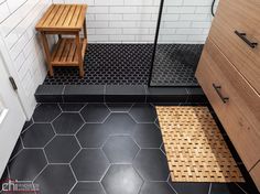 a black and white tiled bathroom with wooden stool