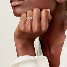 a woman with her hand on her face wearing a gold ring and white shirt, she is looking at the camera