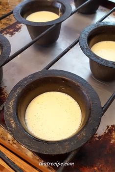 four pots filled with liquid sitting on top of an oven burner next to other cooking utensils