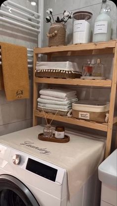 a white washer sitting next to a dryer in a bathroom under a towel rack