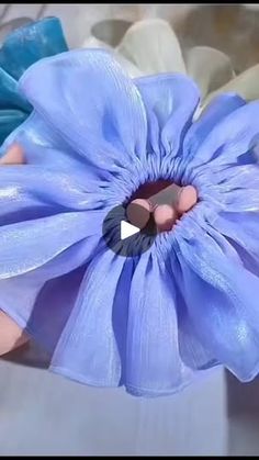 a blue flower being held by someone's hand with an object in the middle