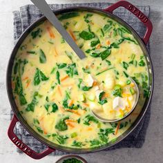 a pot filled with cheese and spinach on top of a table next to a spoon