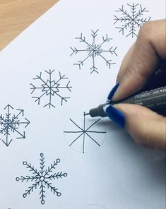 someone is drawing snowflakes on paper with a marker