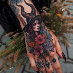 a tattooed woman's hand with flowers and a hat on it