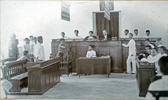 an old black and white photo of people in court room with men sitting at desks