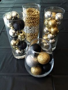 several glass vases with ornaments in them on a black table cloth covered tablecloth