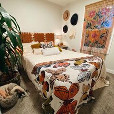 a bed room with a neatly made bed and lots of plants on the wall behind it