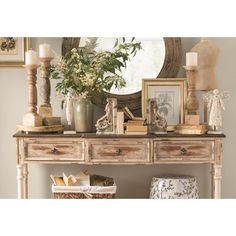 a white table topped with lots of pictures and vases next to a round mirror