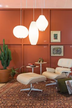 an orange room with two white chairs and a lamp hanging from the ceiling above it