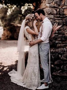 a bride and groom kissing in front of a stone wall