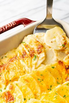 a casserole dish with potatoes in it and a spatula on the side