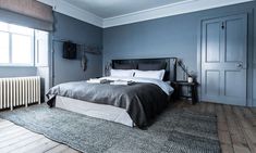 a bedroom with blue walls and wooden floors, along with a bed in the middle