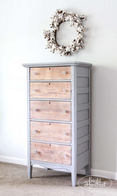 an old dresser is painted gray and has a wreath on top of it with cotton floss