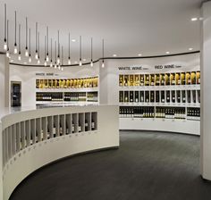 a wine store with several rows of bottles on the wall and lights hanging from the ceiling