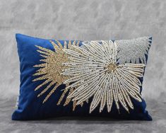 a blue pillow with gold and silver sequins on the front, sitting on a gray surface