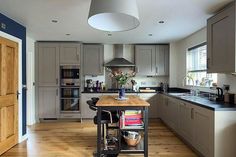 a large kitchen with wooden floors and gray cupboards, an island table in the middle