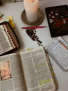 an open book sitting on top of a table next to a candle and other items