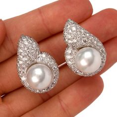 These elegant 1980's diamond and pearl tear drop shaped clip on earrings are crafted in solid 18 karat white gold, weighing 23.6 grams and measuring 30mm x 20mm. Showcasing a pair of prominent lustrous cultured pearls in white creamy color and measuring 13mm in diameter, one with very few natural inclusions. Surrounded by a tear drop shape frame pave-set with 130 round cut diamonds, collectively weighing approximately, 7.50 carats, graded G-H color, and VS1-VS2 clarity. Feature a filigree design Luxury Pear-shaped Diamond Earrings For Evening, Pear-shaped Diamond Earrings For Evening, Diamond Pearl Earrings In White Gold, Pear Shaped, Luxury Teardrop Pearl Earrings With Diamond Accents, Luxury Pear-shaped Pearl Earrings For Anniversary, White Gold Diamond Pear Shaped Pearl Earrings, Luxury Drop Pearl Earrings For Formal Occasions, Luxury Drop Pearl Earrings For Formal Events, Luxury Pear-shaped Pearl Drop Diamond Earrings