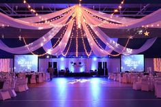 a large room with white drapes and lights on the ceiling is decorated for an event