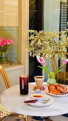 a table topped with plates of food and flowers next to a vase filled with pink roses