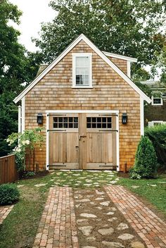 an instagramted photo of a garage with barn doors and brick path leading to the front door