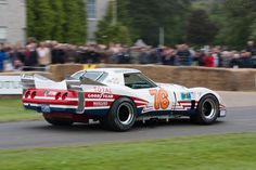 a race car driving around a track with people watching