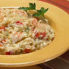 rice with shrimp and parsley in a yellow bowl on a red tablecloth, ready to be eaten