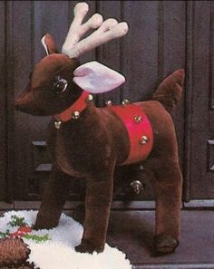 a brown dog standing on top of snow next to a christmas tree and reindeer antlers