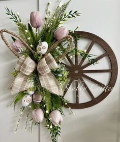 a wreath with flowers and eggs hanging on a door