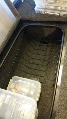 three plastic containers sitting in the back of a truck on top of a floor next to a counter