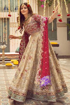 a woman in a red and gold lehenga with flowers hanging from the ceiling