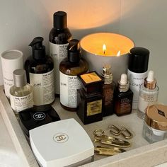 an assortment of skin care products are displayed on a bathroom counter with a lit candle