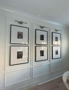 a living room with white walls and pictures on the wall