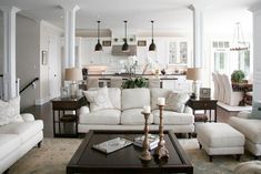 a living room filled with white furniture and lots of pillows on top of it's couches