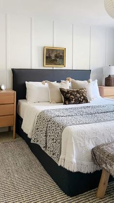 a bed with white sheets and pillows in a bedroom next to a dresser, mirror and lamp