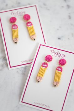 two pairs of earrings with pink beads and yellow corn on the cob, sitting next to each other