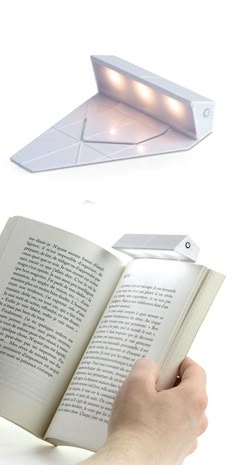 a person is holding an open book in front of a light that looks like a paper airplane