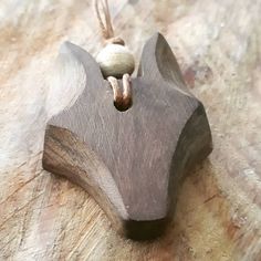 a wooden ornament hanging from a rope on a table top with wood grain