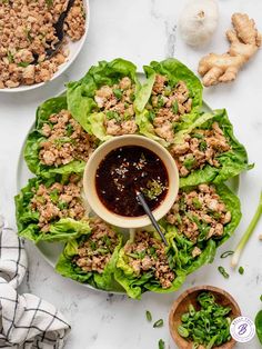 lettuce with meat and sauce on a plate next to two bowls of vegetables