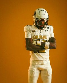 a football player in uniform with his arms crossed and looking at the camera on an orange background