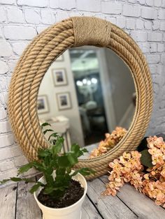 a potted plant sitting on top of a wooden table next to a round mirror