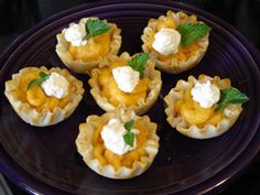 mini pies with whipped cream and mint leaves on a purple plate, ready to be eaten