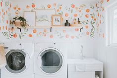 a washer and dryer in a white room with oranges on the wall